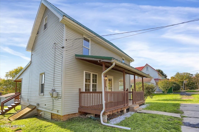 rear view of house featuring a lawn and covered porch