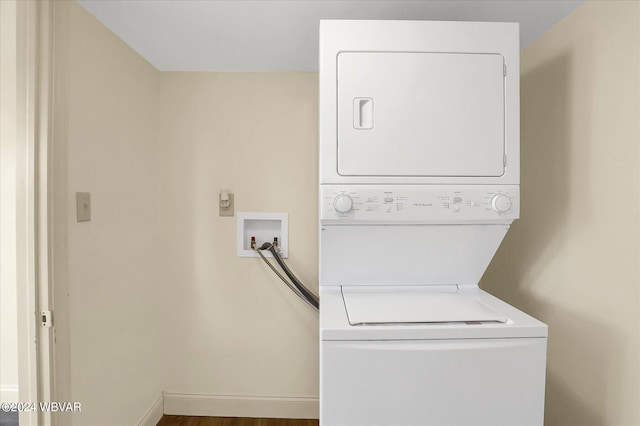 laundry area with stacked washing maching and dryer and hardwood / wood-style flooring