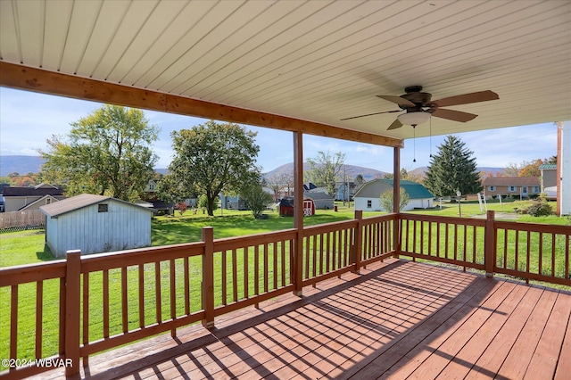 wooden terrace featuring ceiling fan, a shed, and a yard