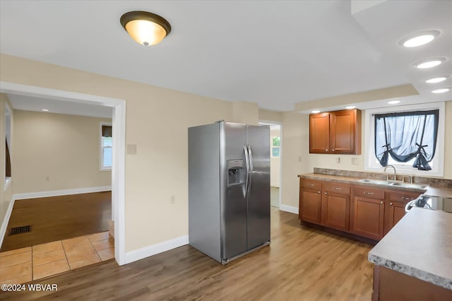 kitchen featuring stainless steel refrigerator with ice dispenser, light hardwood / wood-style flooring, a wealth of natural light, and sink