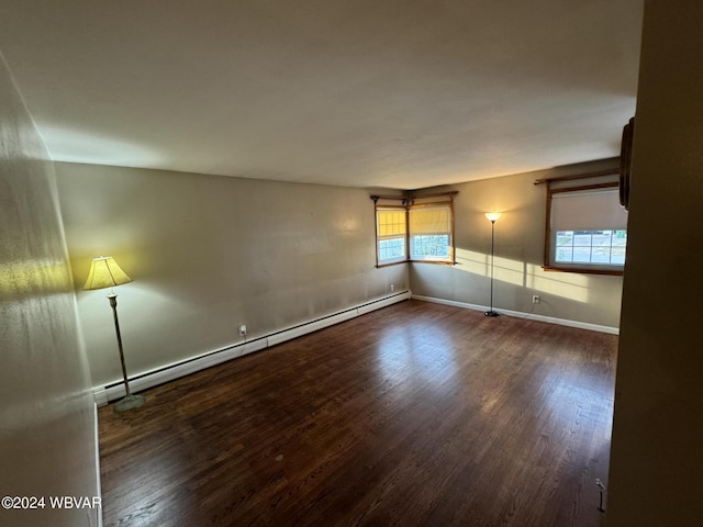 empty room with a baseboard heating unit, dark hardwood / wood-style flooring, and a healthy amount of sunlight