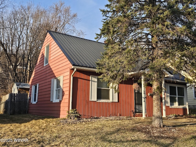 view of front of property featuring metal roof, a front lawn, and fence