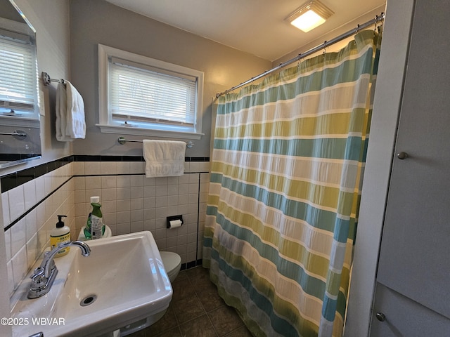 bathroom with a shower with curtain, a wainscoted wall, a sink, tile patterned floors, and toilet