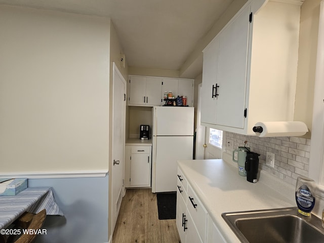 kitchen with freestanding refrigerator, light countertops, white cabinets, light wood-style floors, and tasteful backsplash