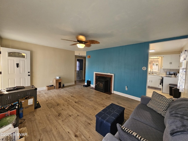 living room featuring light wood-style flooring, a ceiling fan, and baseboards