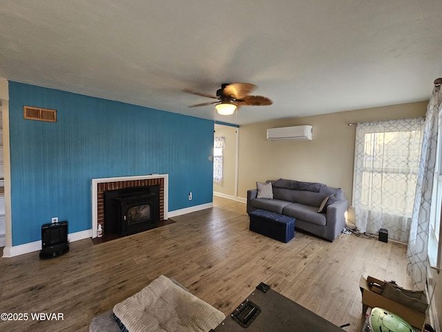 living area with visible vents, baseboards, a wall mounted air conditioner, wood finished floors, and a ceiling fan