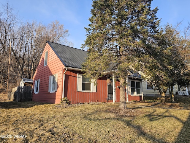 view of front of property featuring metal roof, a front lawn, and fence