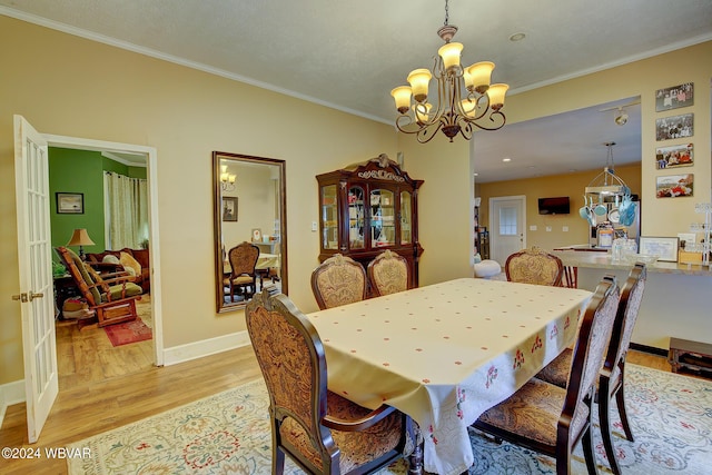 dining area featuring light hardwood / wood-style flooring, crown molding, and an inviting chandelier