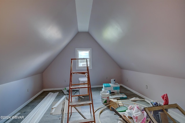 interior space featuring lofted ceiling, wood finished floors, and baseboards