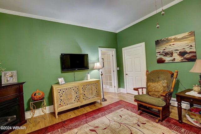 living room featuring baseboards, a fireplace, ornamental molding, and wood finished floors