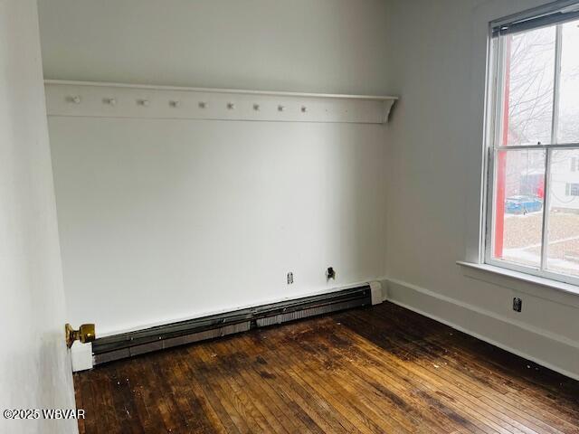 laundry room featuring baseboard heating and hardwood / wood-style flooring