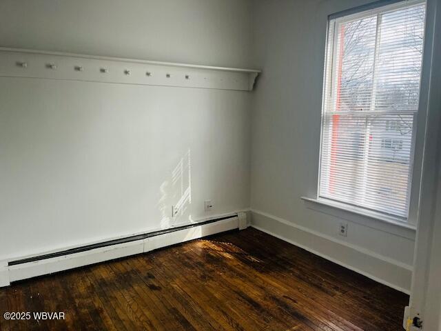 spare room with a baseboard radiator, dark wood-style flooring, and baseboards