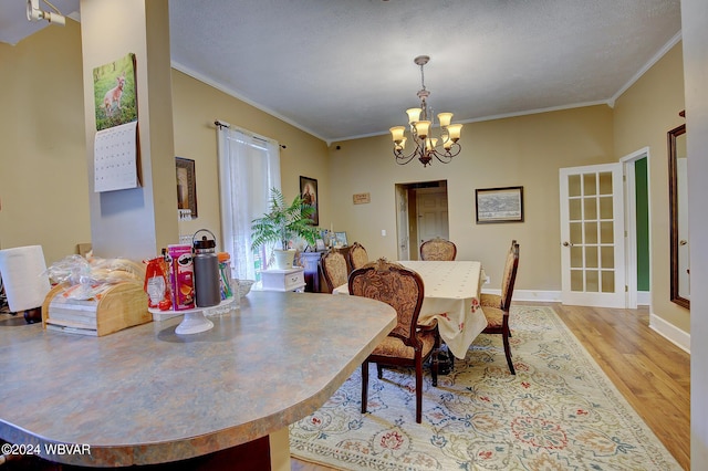 dining room featuring an inviting chandelier, crown molding, a textured ceiling, and light hardwood / wood-style floors