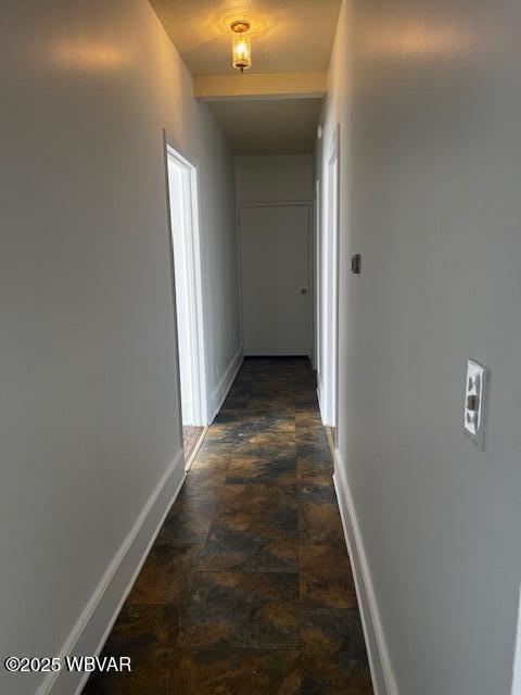 hallway featuring baseboards and stone finish floor