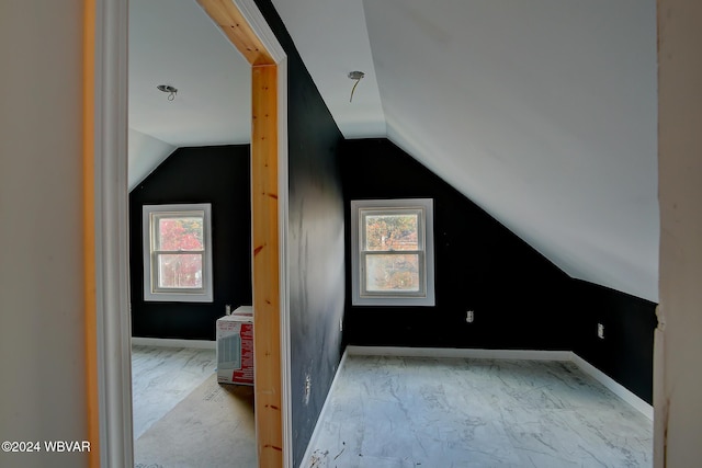 bonus room featuring vaulted ceiling, marble finish floor, plenty of natural light, and baseboards