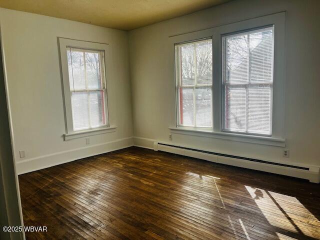 unfurnished room with baseboards, a baseboard heating unit, and dark wood-type flooring