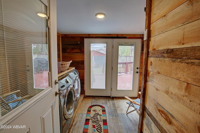 laundry area with washer and dryer, wood walls, and light hardwood / wood-style floors