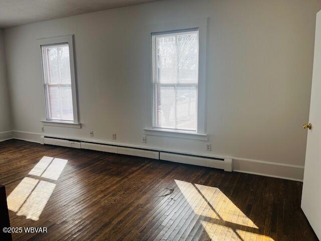 spare room with a baseboard radiator, wood-type flooring, baseboards, and a wealth of natural light