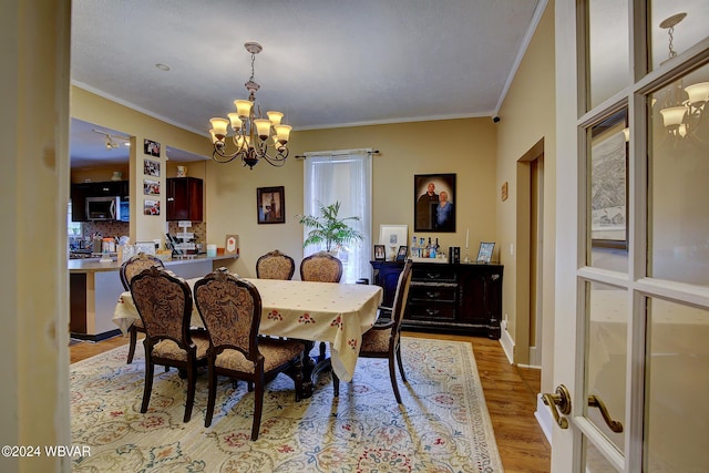 dining area with light hardwood / wood-style floors, a chandelier, and ornamental molding