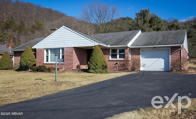 ranch-style home with brick siding, a shingled roof, an attached garage, a front yard, and driveway