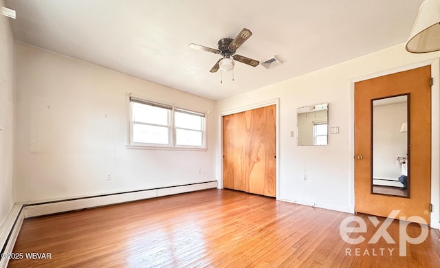 unfurnished bedroom featuring a closet, wood-type flooring, visible vents, baseboard heating, and ceiling fan