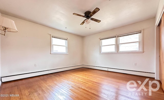 spare room with hardwood / wood-style floors, baseboard heating, and a ceiling fan