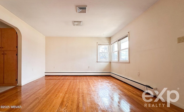 spare room featuring visible vents, arched walkways, and wood finished floors