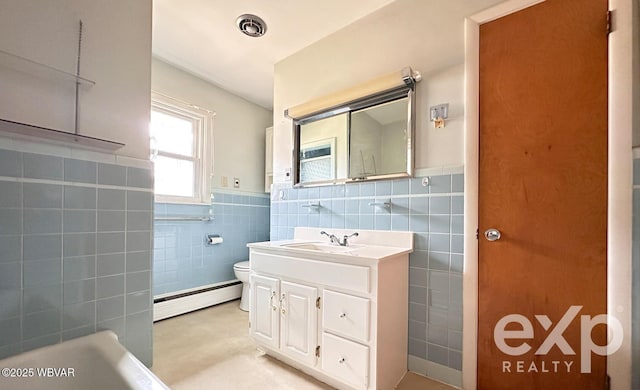 bathroom with visible vents, toilet, vanity, a baseboard heating unit, and tile walls