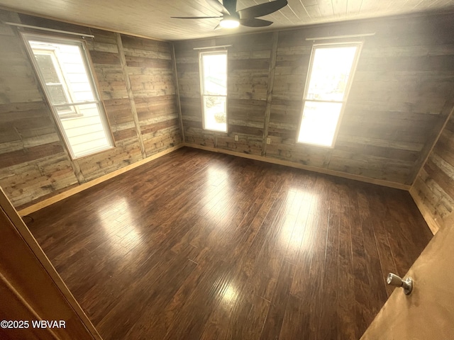 empty room with dark hardwood / wood-style floors, ceiling fan, and wooden walls