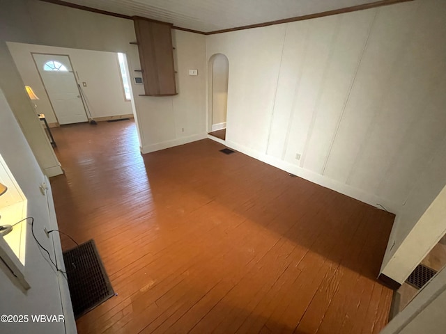 unfurnished living room featuring dark wood-type flooring and crown molding