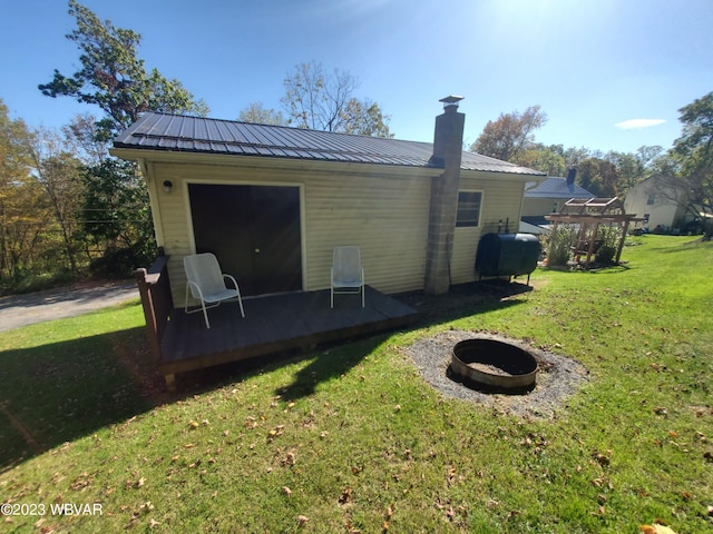 rear view of house with a yard and an outdoor fire pit