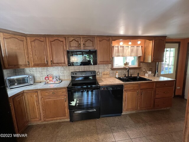 kitchen featuring decorative backsplash, sink, light tile patterned floors, and black appliances