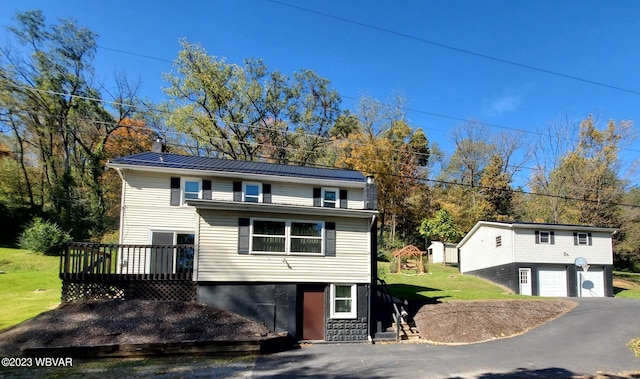 view of front facade with a garage, a deck, an outdoor structure, and a front lawn