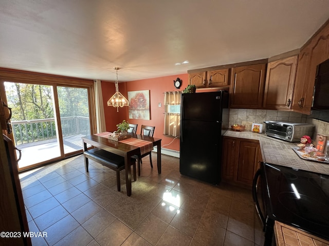 kitchen featuring backsplash, a baseboard heating unit, black appliances, decorative light fixtures, and an inviting chandelier