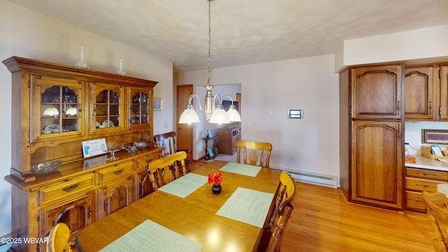 dining space featuring a chandelier, baseboard heating, and light wood finished floors