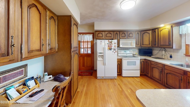 kitchen with tasteful backsplash, light countertops, light wood-style floors, brown cabinetry, and white appliances