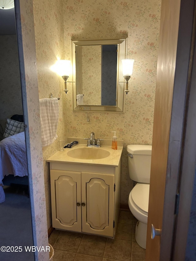 ensuite bathroom with wallpapered walls, toilet, and tile patterned flooring