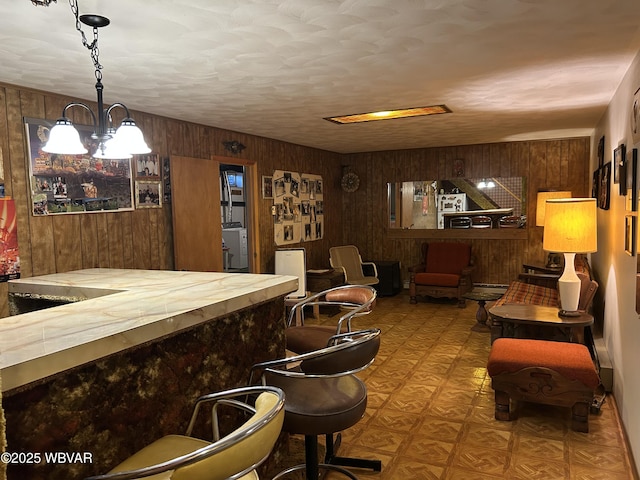 bar featuring tile patterned floors, wood walls, and an inviting chandelier