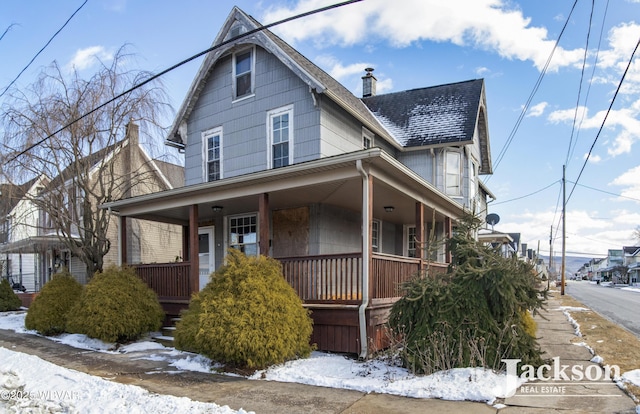 view of front of house featuring a porch, roof with shingles, and a chimney