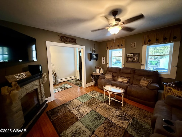 living room with wood finished floors, a ceiling fan, baseboards, and a baseboard heating unit