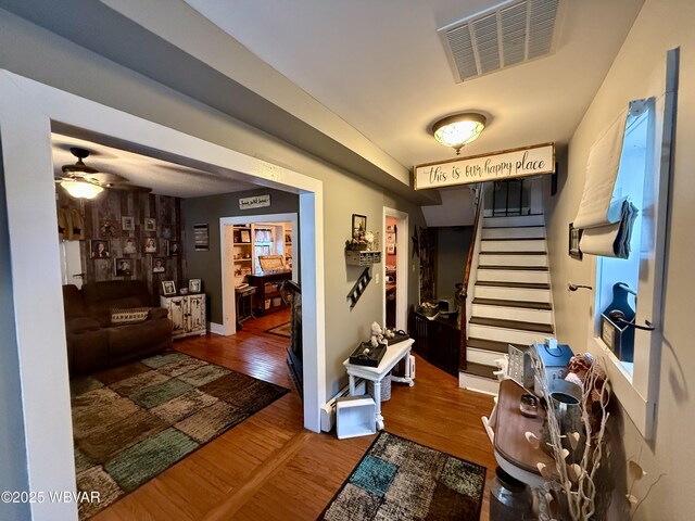 entryway featuring ceiling fan, wood finished floors, stairs, and visible vents