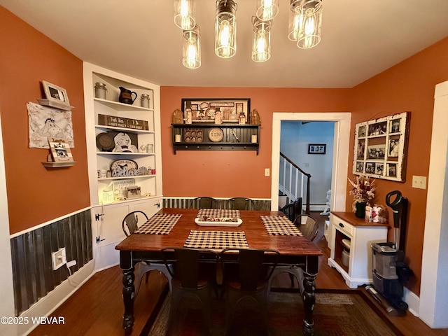 dining area featuring stairs, wood finished floors, an inviting chandelier, and built in features
