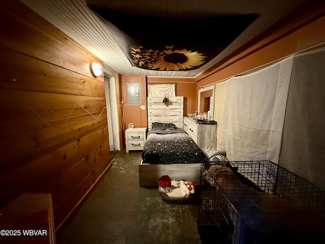 interior space with concrete flooring, electric panel, and wood walls