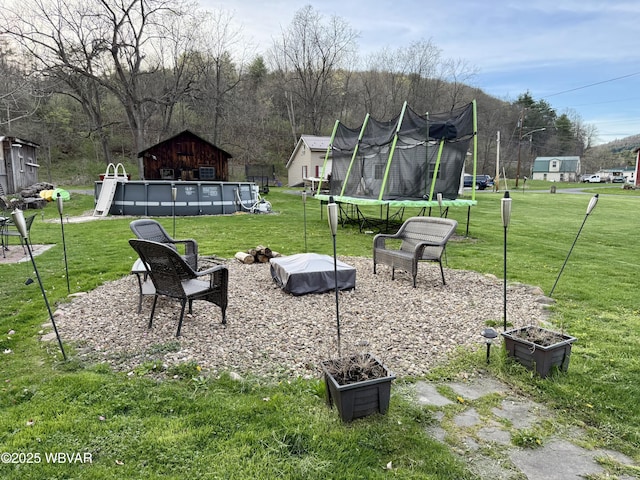 view of yard featuring an outdoor pool and a trampoline
