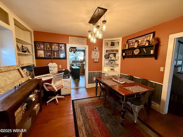 office area featuring a baseboard heating unit, a chandelier, wood finished floors, and built in shelves
