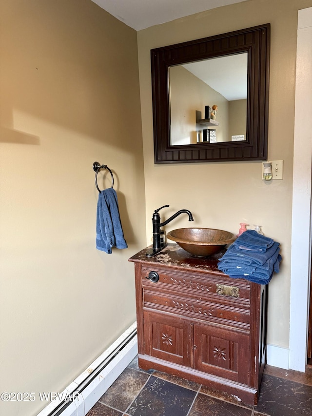 bathroom with baseboard heating, baseboards, stone tile floors, and vanity