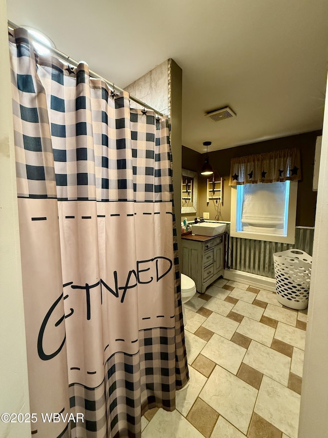 full bath featuring toilet, vanity, curtained shower, and visible vents