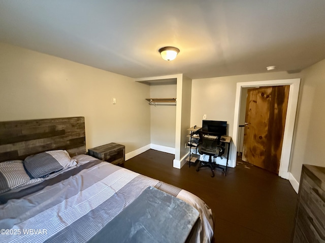 bedroom with wood finished floors, a closet, and baseboards