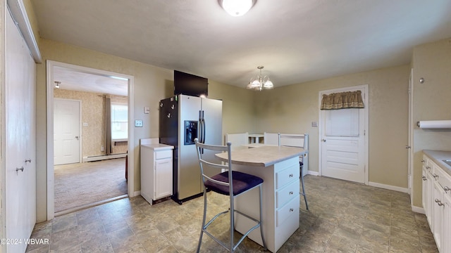 kitchen with stainless steel refrigerator with ice dispenser, white cabinets, a center island, hanging light fixtures, and a breakfast bar area