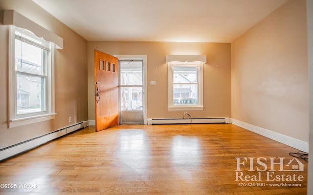 entrance foyer featuring a baseboard heating unit, light hardwood / wood-style flooring, and a healthy amount of sunlight